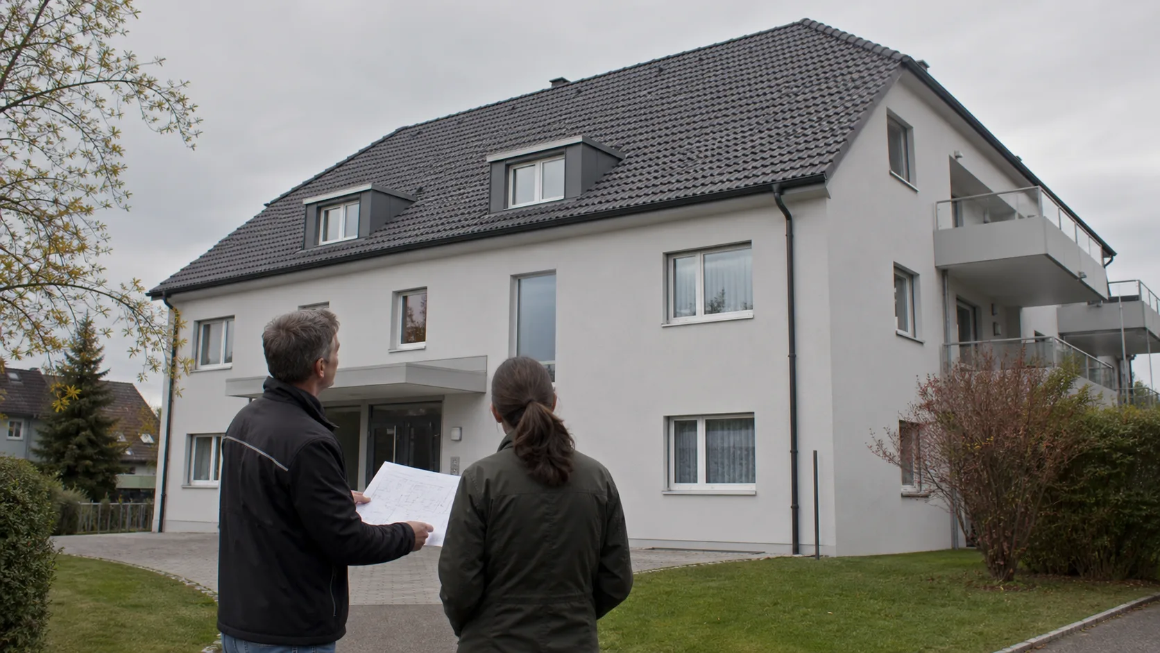 Hausbesitzer und Dachfachperson besprechen den Unterhalt einer Bedachung vom sicheren Hof aus